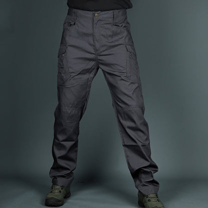 Graue taktische Hose mit mehreren Taschen, robustem Material und militärischem Design, getragen mit olivgrünen Stiefeln vor grauem Hintergrund.