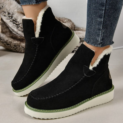 Schwarze Damen-Winterstiefel mit weißem Kunstfellfutter und grüner Sohle, getragen mit blauen Jeans. Bequeme, warme Schuhe für kalte Tage.