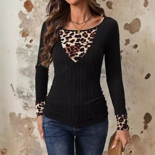 Frau trägt schwarzes Langarmshirt mit Leopardenmuster an Ausschnitt und Ärmeln, kombiniert mit blauer Jeans. Modetrend, Damenbekleidung, Herbstmode.