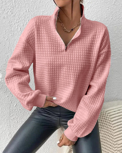 Frau in rosa Stepp-Pullover mit Reißverschluss und Kette, trägt schwarze Lederhose. Modetrend, Damenmode, Herbstoutfit, stilvoller Look.