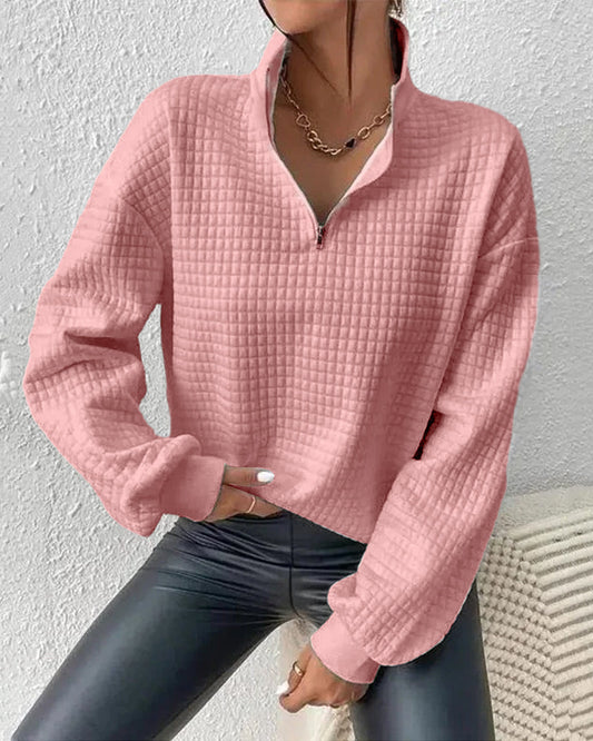 Frau in rosa Stepp-Pullover mit Reißverschluss und Kette, trägt schwarze Lederhose. Modetrend, Damenmode, Herbstoutfit, stilvoller Look.