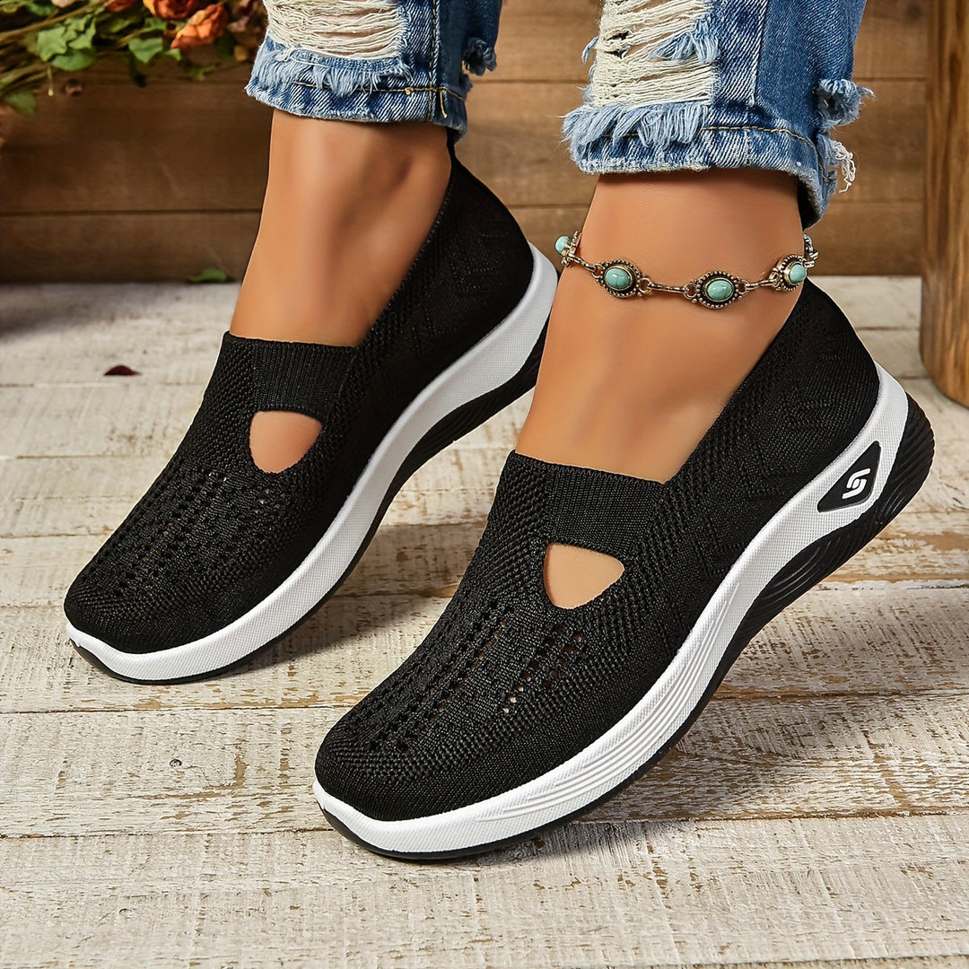 Schwarze Damen-Sneaker mit Keilabsatz, atmungsaktivem Strickmaterial und weißer Sohle, getragen mit zerrissenen Jeans und türkisfarbenem Fußkettchen.