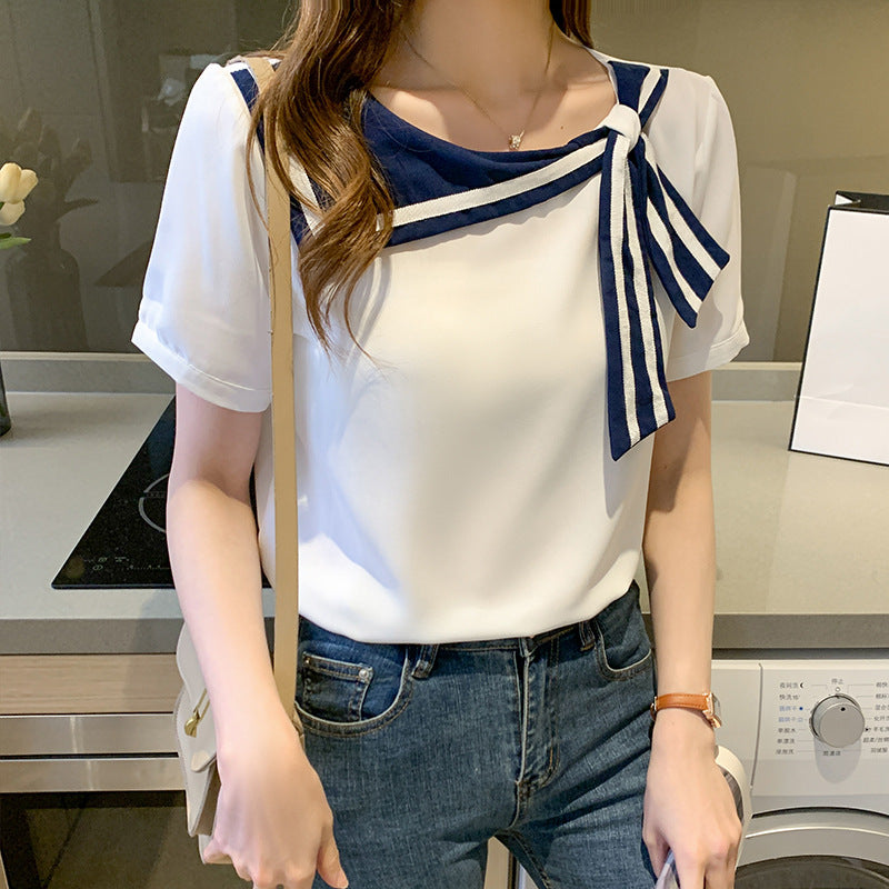 Frau trägt weißes Blusenshirt mit blauem Schleifendetail, kombiniert mit Jeans. Modetrend, eleganter Freizeitlook, stilvolle Damenbekleidung.