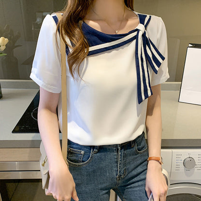 Frau trägt weißes Blusenshirt mit blauem Schleifendetail, kombiniert mit Jeans. Modetrend, eleganter Freizeitlook, stilvolle Damenbekleidung.