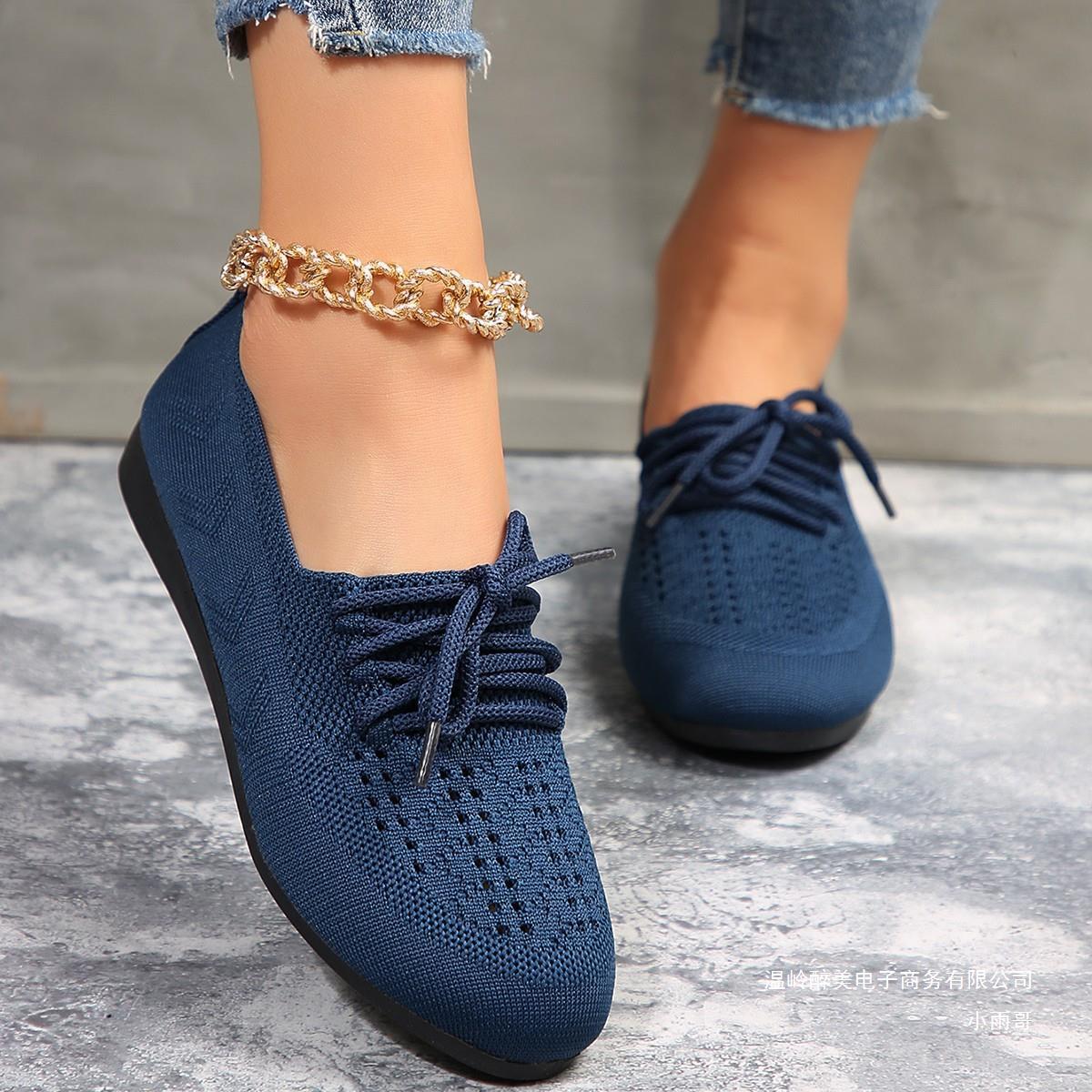 Damenfüße in blauen Strick-Sneakern mit goldener Fußkette, Jeans. Modische, bequeme Schuhe, ideal für Freizeit und Alltag. Trendige Damenmode.