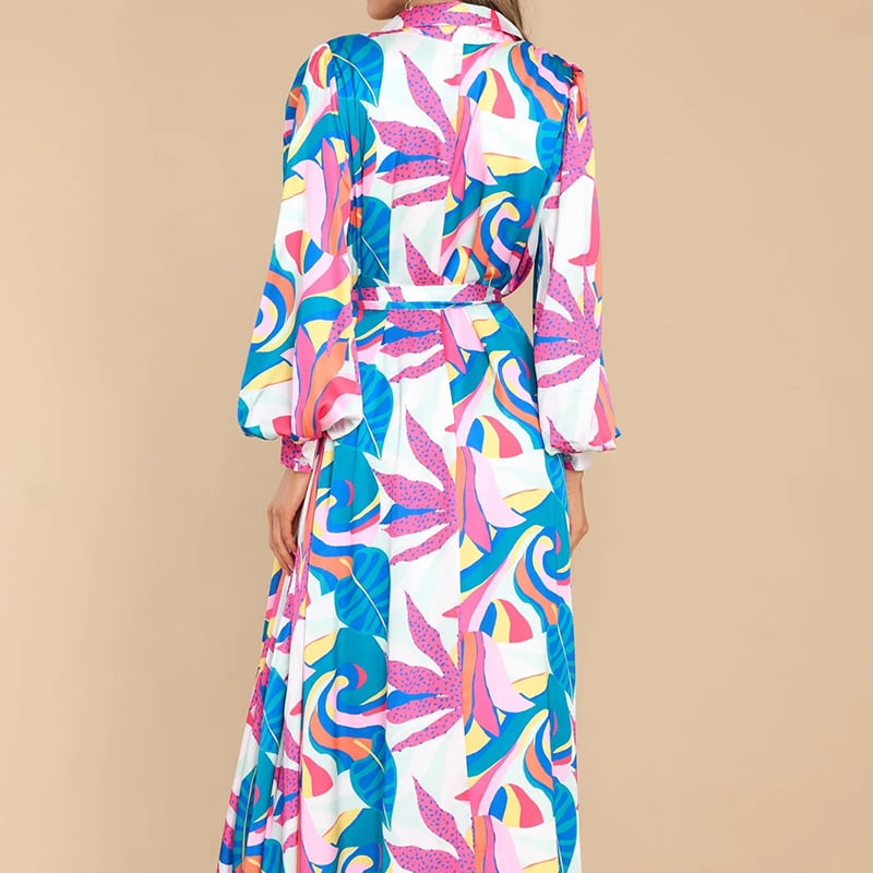 Frau in langem, buntem Kleid mit abstraktem Muster, Rückansicht. Modetrend 2023, farbenfrohes Design, eleganter Stil, Damenmode.