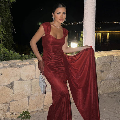 Frau in elegantem, rotem Abendkleid posiert vor Steinmauer bei Nacht; glamouröses Outfit, Abendmode, stilvolle Abendveranstaltung.