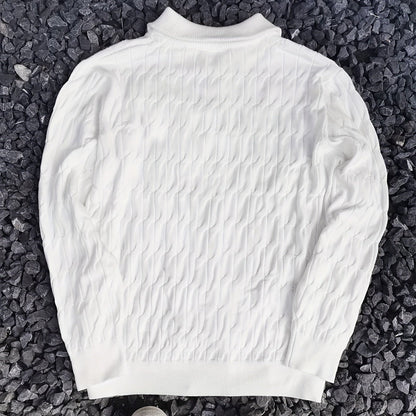 Weißer Strickpullover mit Zopfmuster auf grauem Kieshintergrund. Modischer Herrenpullover, warm und stilvoll für Herbst und Winter.