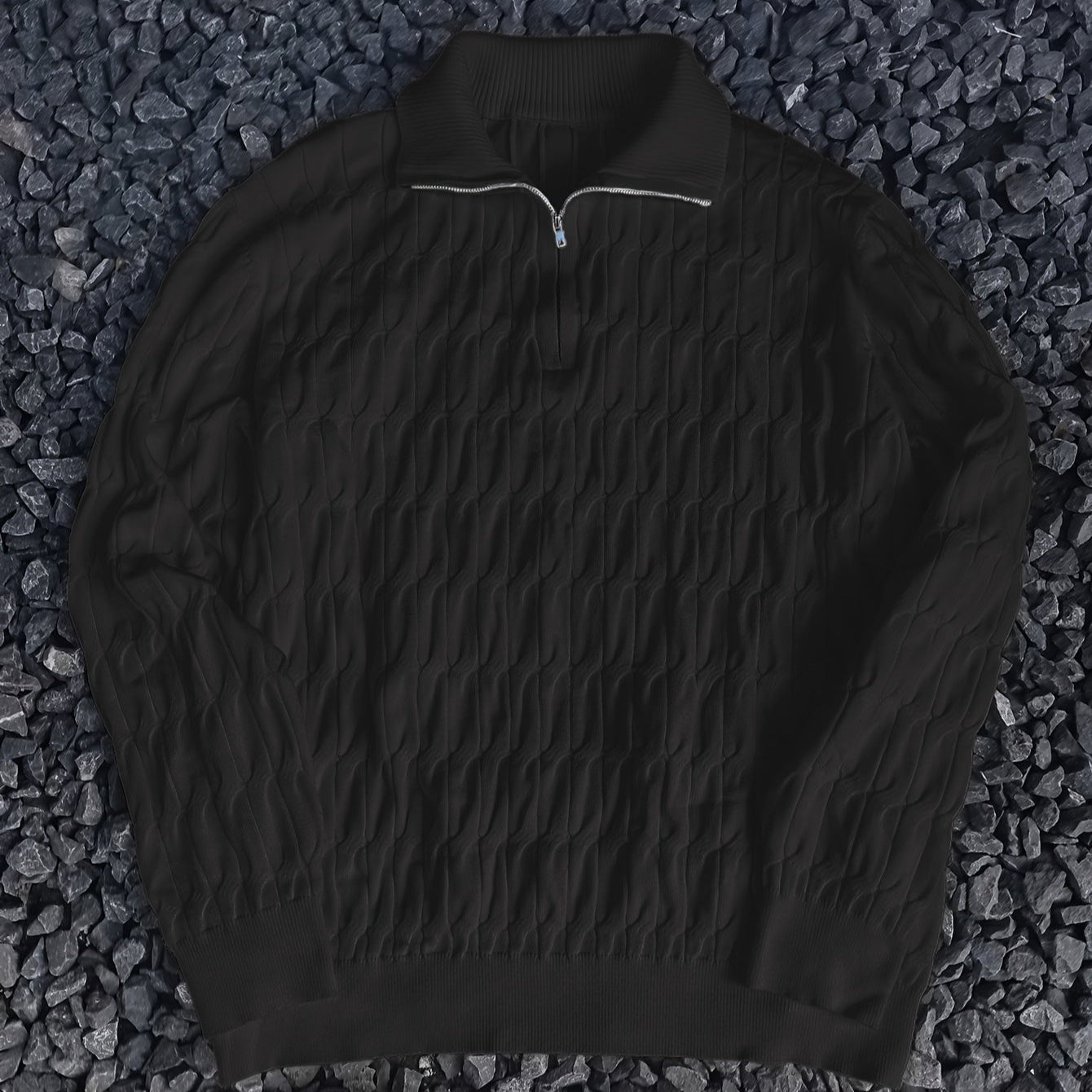 Schwarzer Strickpullover mit Reißverschluss auf dunklem Kieshintergrund. Modischer Herrenpullover, warm und stilvoll für Herbst und Winter.