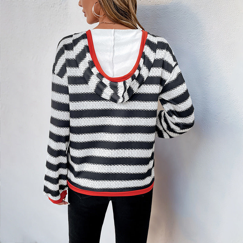 Frau in gestreiftem Kapuzenpullover mit schwarz-weißen Streifen und roten Akzenten, Rückansicht, lässige Mode, Herbstbekleidung.