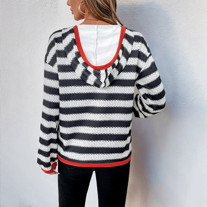 Frau in gestreiftem Kapuzenpullover mit schwarz-weißen Streifen und roten Akzenten, Rückansicht, lässige Mode, Herbstbekleidung.