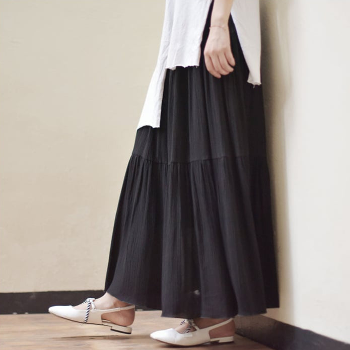 Schwarzer Maxirock und weiße Bluse, kombiniert mit eleganten weißen Schnürschuhen. Modetrend, Damenmode, stilvoller Look.