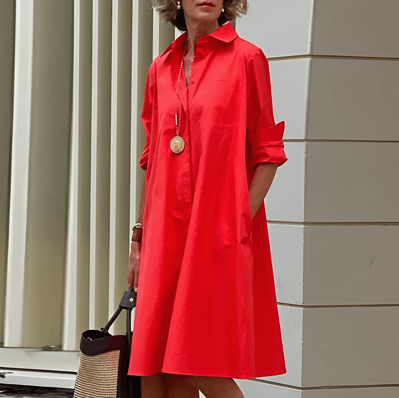 Frau in rotem Hemdkleid mit langen Ärmeln, trägt eine goldene Halskette und hält eine schwarze Tasche. Mode, Damenbekleidung, eleganter Stil.