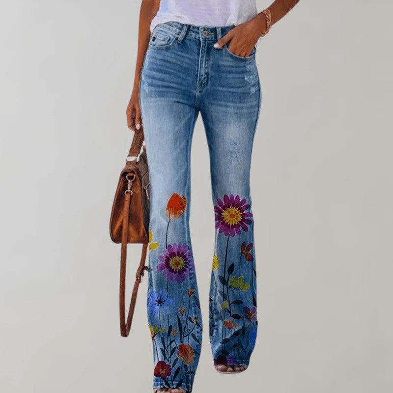 Frau in blauer Jeans mit buntem Blumenmuster, weißem T-Shirt und brauner Handtasche. Modetrend, Damenjeans, florales Design.
