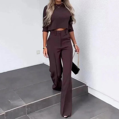 Frau in eleganter, dunkelbrauner Hose und passendem Crop-Top, trägt schwarze Handtasche, geht Treppe hinunter. Mode, Damenbekleidung, Streetstyle.