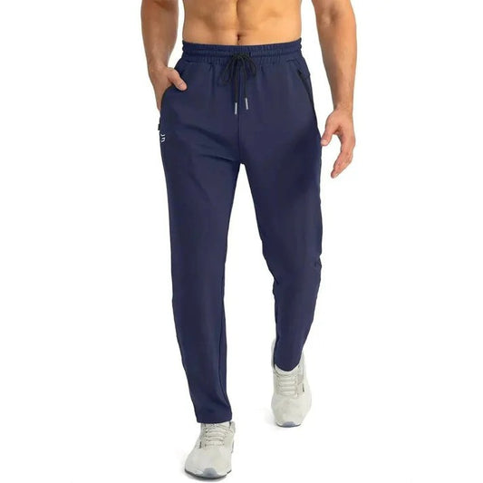 Mann in blauer Jogginghose und grauen Turnschuhen, sportliche Kleidung, Fitnessmode, bequeme Sporthose, ideal für Training und Freizeit.