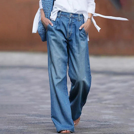 Weite Damenjeans im Vintage-Stil, kombiniert mit weißem Hemd und blauer Tasche. Modetrend, lässiger Look, bequeme Passform.