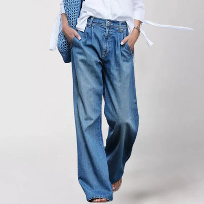 Frau in blauer, weiter Jeanshose und weißem Hemd, trägt eine blaue Tasche. Modetrend, lässiger Stil, Damenmode, bequeme Kleidung.