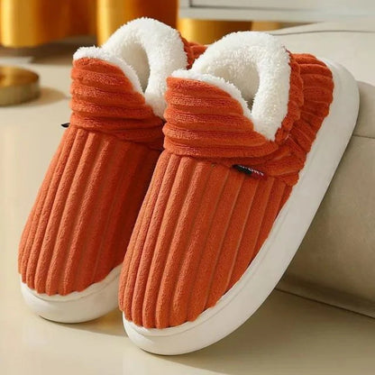 Orange Plüsch-Hausschuhe mit weißem Futter auf beigem Hintergrund. Bequeme, warme Pantoffeln für den Winter. Ideal für gemütliche Abende zu Hause.