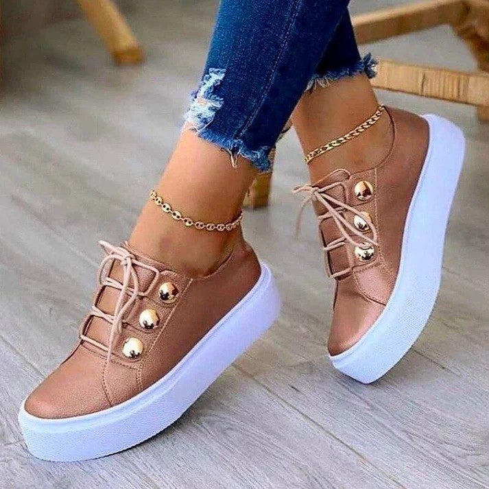 Damen Sneaker in Roségold mit Plateau-Sohle, goldenen Knöpfen und Jeans. Modische Schuhe, ideal für Freizeit und Streetstyle.