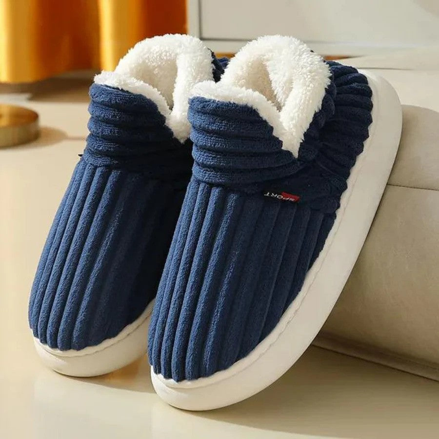 Blaue Hausschuhe mit weißem Fleecefutter, rutschfeste Sohle, gemütlich und warm, ideal für den Winter, auf hellem Hintergrund.