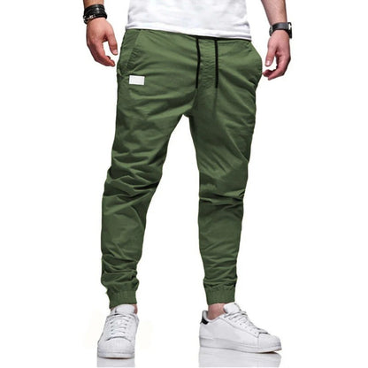 Grüne Jogginghose für Herren, lässig und bequem, mit elastischem Bund und Kordelzug, kombiniert mit weißen Sneakers. Ideal für Freizeit und Sport.