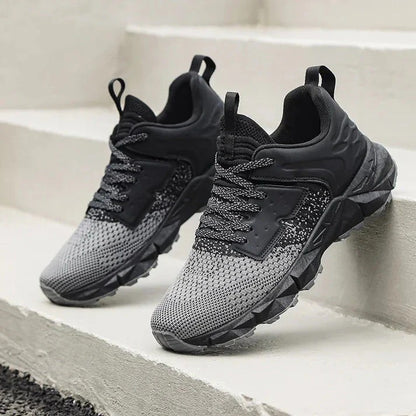 Graue und schwarze Sportschuhe auf Treppe, atmungsaktives Mesh-Obermaterial, rutschfeste Sohle, ideal für Laufen und Fitness.