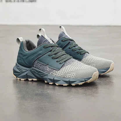 Graue und blaue Sportschuhe auf grauem Boden, modernes Design, atmungsaktives Mesh, robuste Sohle, ideal für Laufen und Fitness.