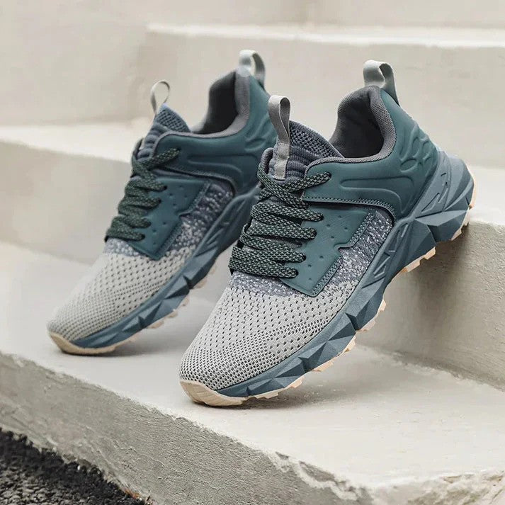 Graue und grüne Sportschuhe auf Treppe, modernes Design, atmungsaktives Mesh, rutschfeste Sohle, ideal für Laufen und Outdoor-Aktivitäten.