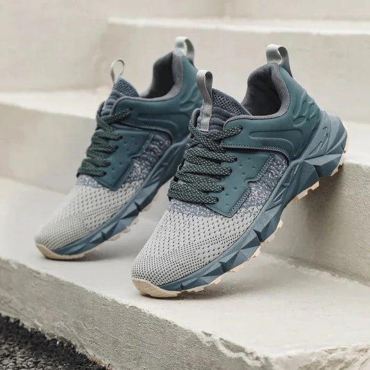 Graue und grüne Sportschuhe auf Treppe, modernes Design, atmungsaktives Mesh, rutschfeste Sohle, ideal für Laufen und Outdoor-Aktivitäten.