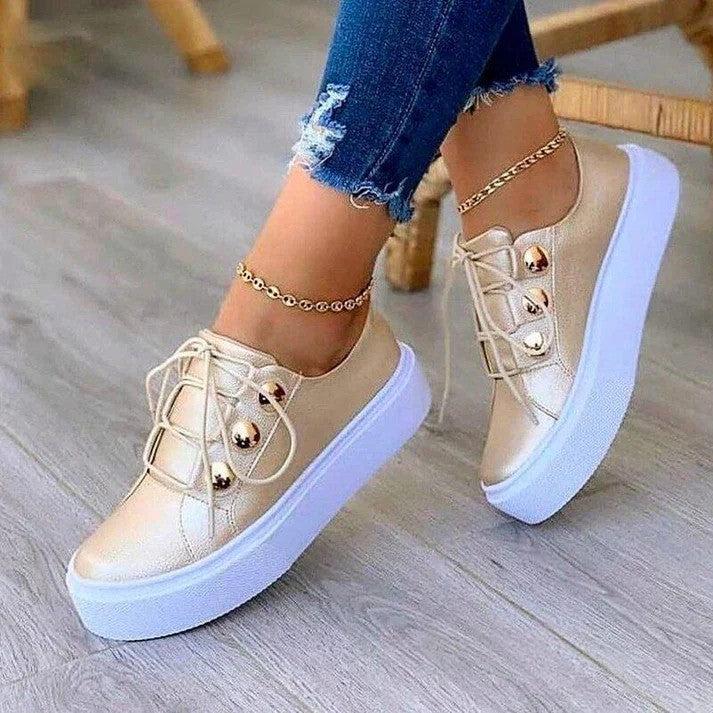 Goldene Sneaker mit Plateau-Sohle, getragen von Person in zerrissenen Jeans. Modische Damen-Schuhe, ideal für trendige Freizeit-Outfits.