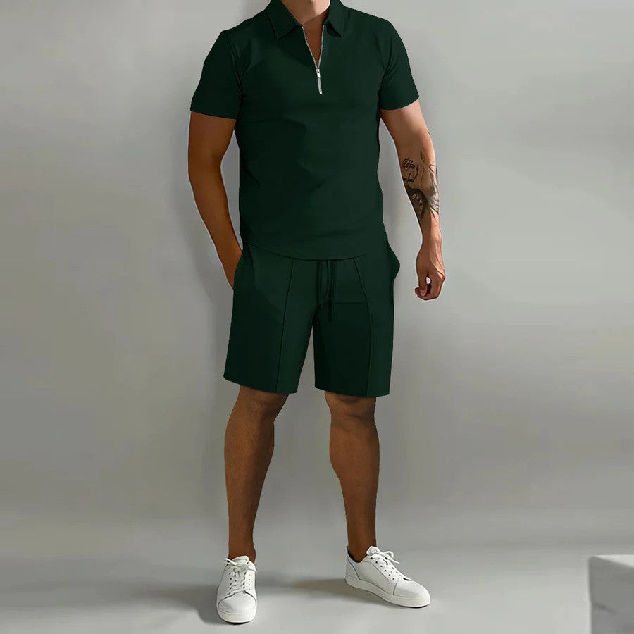 Mann in dunkelgrünem Poloshirt und Shorts, weiße Sneaker, grauer Hintergrund. Sommermode, Herrenbekleidung, sportlich-eleganter Look.