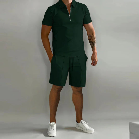 Mann in dunkelgrünem Poloshirt und Shorts, weiße Sneaker, grauer Hintergrund. Sommermode, Herrenbekleidung, sportlich-eleganter Look.