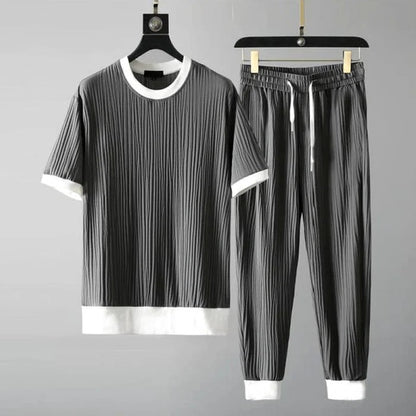 Graues Herren-Set aus T-Shirt und Jogginghose mit weißen Bündchen, geripptes Design, lässige Mode, bequemes Freizeitoutfit, auf Kleiderbügeln.