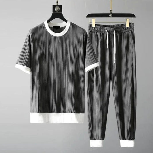 Graues Herren-Set aus T-Shirt und Jogginghose mit weißen Bündchen, geripptes Design, lässige Mode, bequemes Freizeitoutfit, auf Kleiderbügeln.