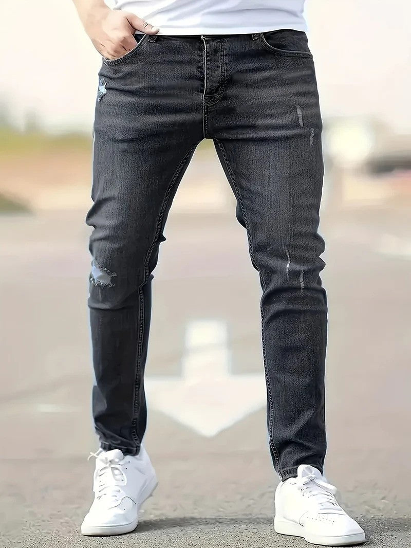 Mann in dunkler Jeans und weißen Sneakers auf Straße. Modetrend, Herrenbekleidung, lässiger Stil, Denim, Freizeitlook.