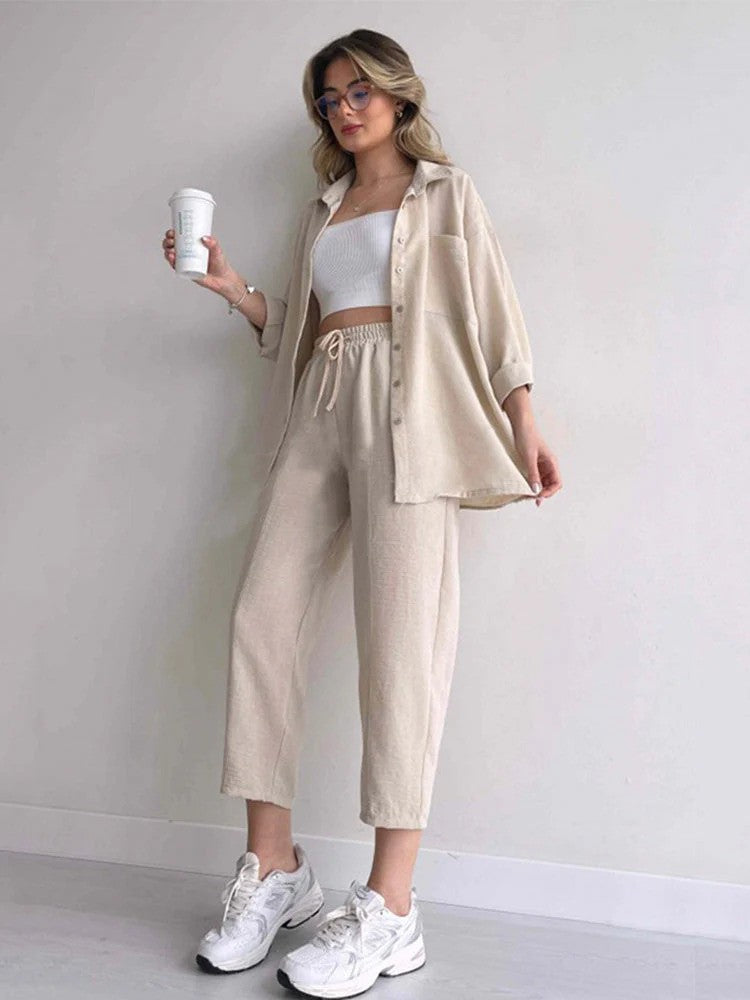 Frau in beiger Freizeitkleidung mit weißem Top und Sneakers, hält Kaffeebecher. Modetrend, lässiger Look, Streetstyle, Damenmode.