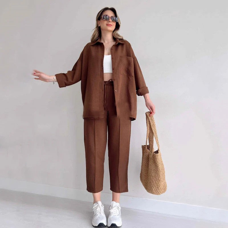 Frau in braunem Leinenanzug mit weißem Top und Sneakers, hält eine Strohtasche. Modetrend, lässiger Stil, Sommeroutfit, Damenmode.