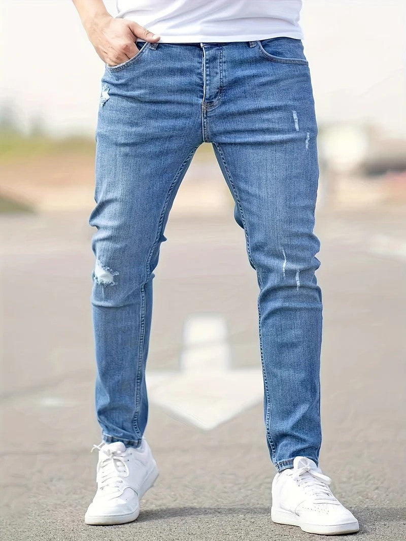 Mann in blauer, zerrissener Jeans und weißen Sneakers auf Straße. Modetrend, lässiger Stil, Herrenbekleidung, Denim-Look.