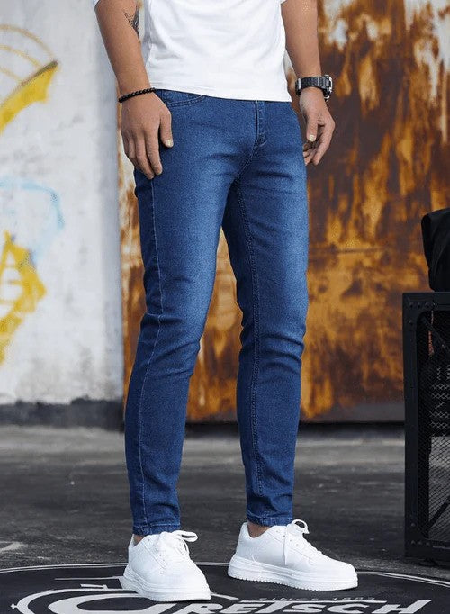 Mann in blauer Jeans und weißen Sneakers vor urbanem Hintergrund. Modetrend, Herrenmode, lässiger Stil, Streetwear, Denim-Look.
