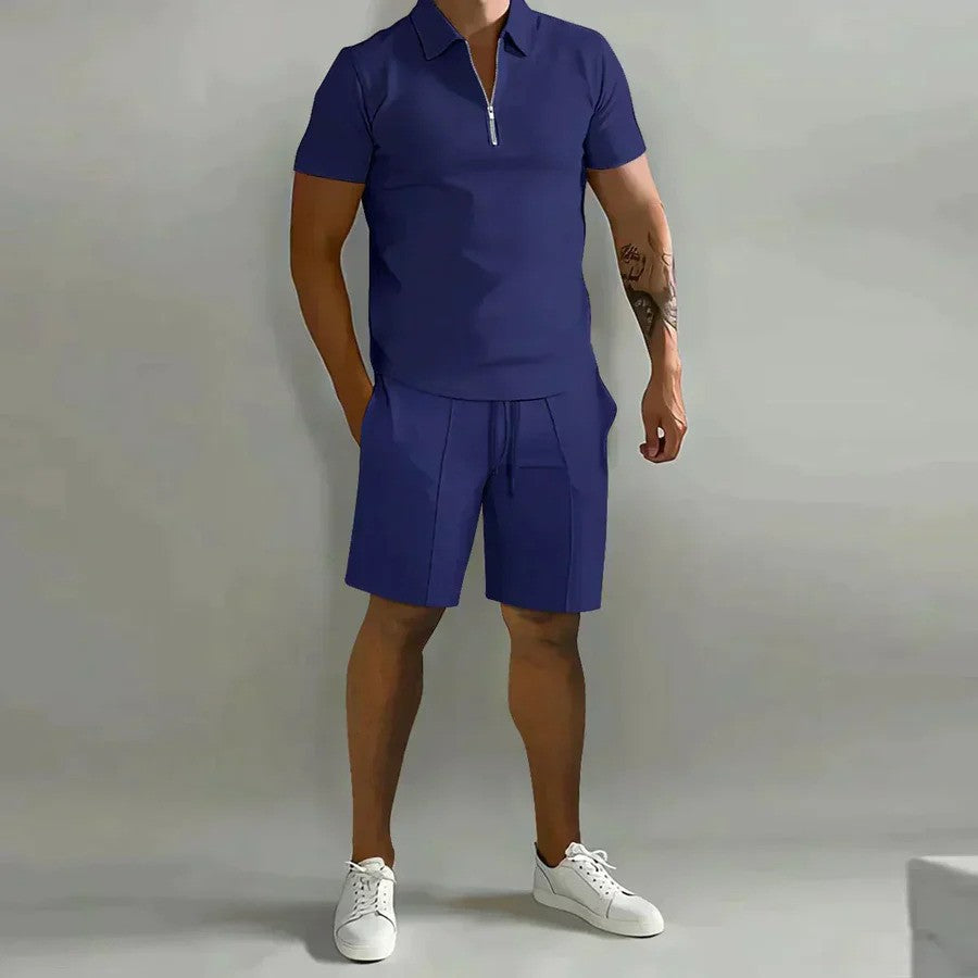 Ein Mann trägt ein blaues Poloshirt und passende Shorts, kombiniert mit weißen Sneakers. Modernes Sommeroutfit, lässiger Stil, Herrenmode.