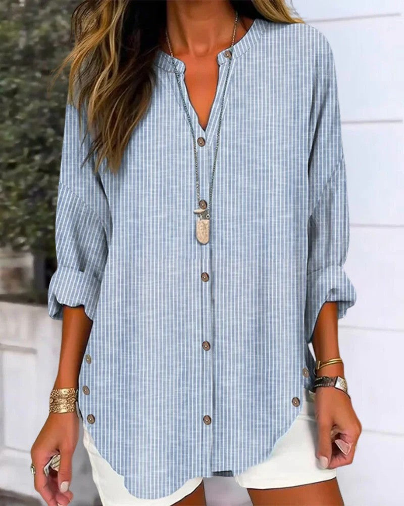 Frau trägt blau-weiß gestreifte Bluse mit Knopfleiste und langen Ärmeln, kombiniert mit weißem Rock. Modetrend, lässiger Sommerlook.