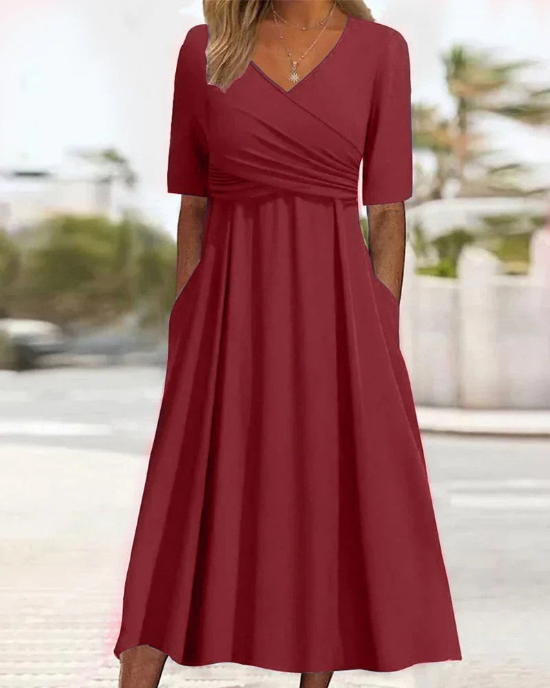 Rotes Damenkleid mit V-Ausschnitt und kurzen Ärmeln, knielang, aus fließendem Stoff, ideal für Sommermode. Elegantes Design mit Taschen.