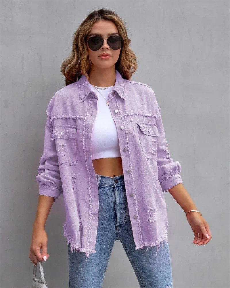 Frau in lila Jeansjacke, weißem Crop-Top und blauer Jeans vor grauem Hintergrund. Modetrend, lässiger Stil, Sonnenbrille.