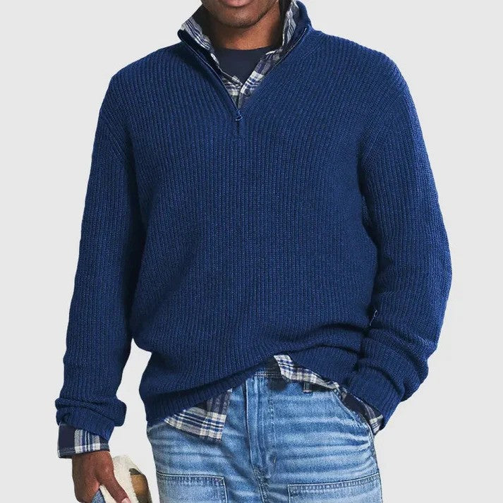 Blauer Herrenpullover mit Reißverschluss, kombiniert mit kariertem Hemd und Jeans. Modischer Freizeitlook für Männer.