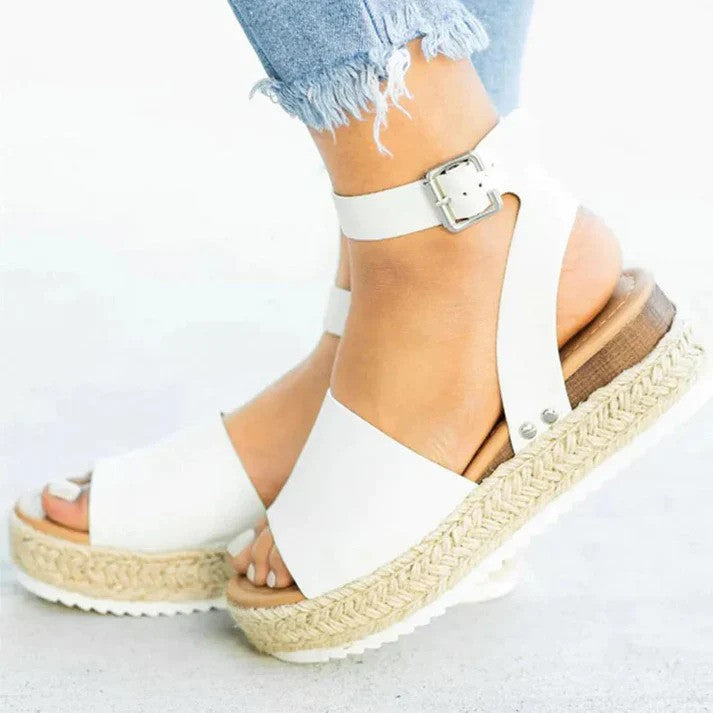 Weiße Sandalen mit Plateau und Knöchelriemen, getragen mit zerrissenen Jeans. Modische Sommerschuhe, ideal für Damenmode und Freizeitoutfits.
