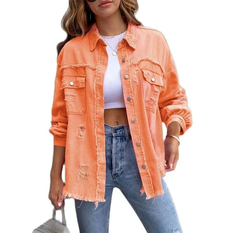 Frau in orangefarbener, zerrissener Jeansjacke, weißem Crop-Top und blauen Jeans. Modetrend, lässiger Streetstyle, Damenmode.