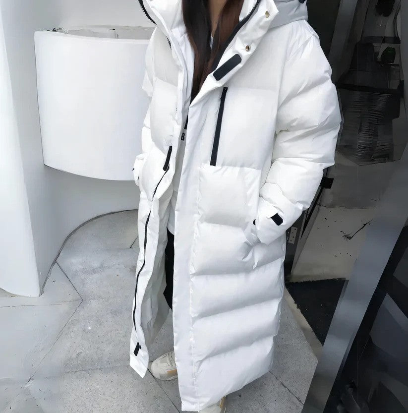 Frau in langem weißen Daunenmantel mit Kapuze, moderne Wintermode, warme Outdoor-Bekleidung, stilvoller Look für kalte Tage.
