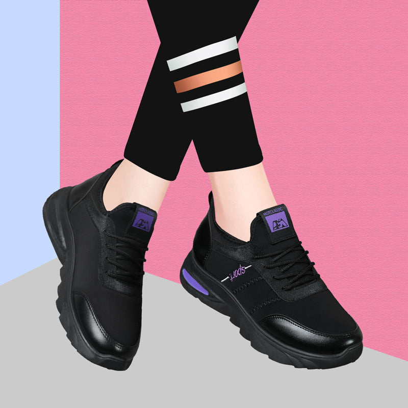 Schwarze Damen-Sneaker mit lila Akzenten, getragen von Person in Leggings vor rosa-blauem Hintergrund. Modische Sportschuhe, bequeme Damenmode.