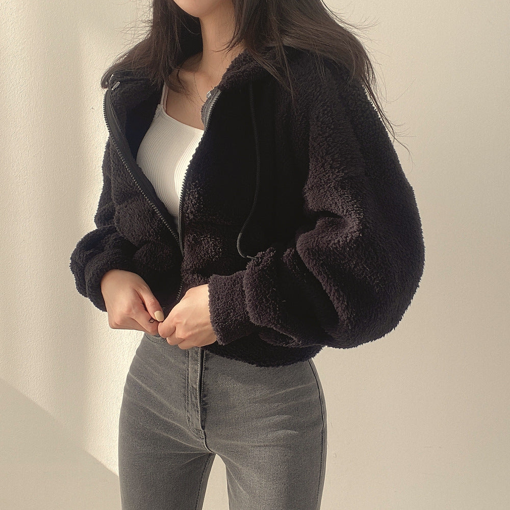 Frau in schwarzer Teddyjacke und grauer Jeans vor weißem Hintergrund. Modetrend, Winterjacke, lässiger Stil, Damenbekleidung.
